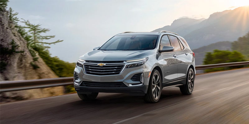 A silver 2023 Chevrolet Equinox driving through a mountain pass