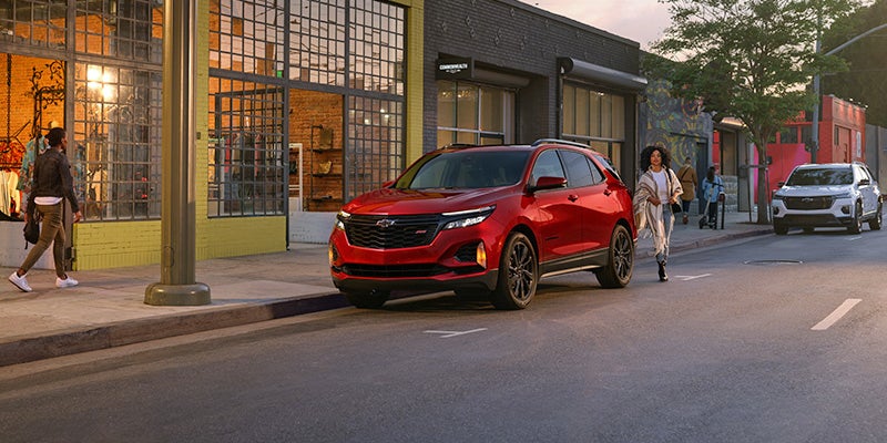 A woman approaching a red Chevrolet Equinox parked on a city street