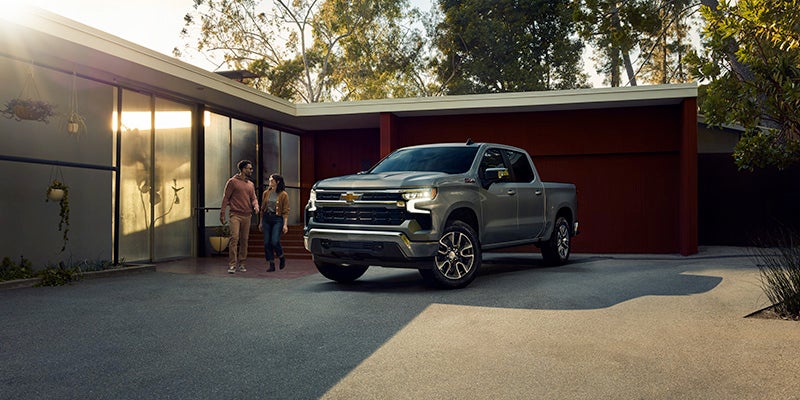 A couple standing outside by their Chevrolet Silverado in the driveway