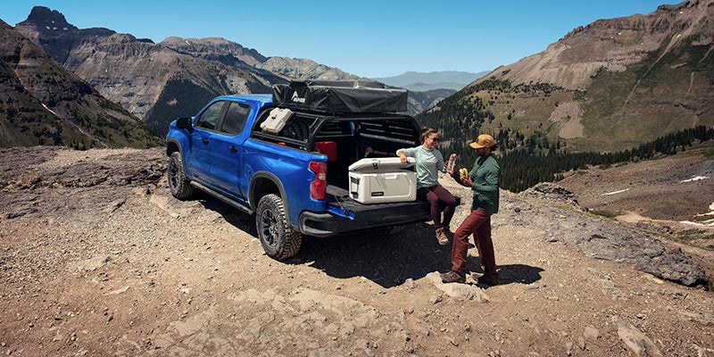 A couple having a picnic at the back of their Chevrolet Silverado in the mountains